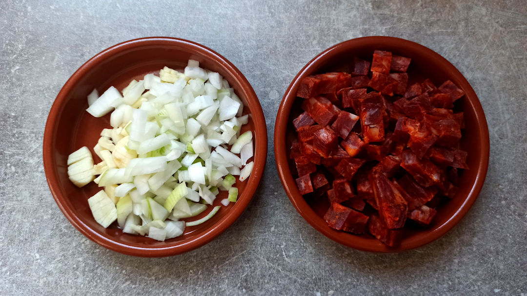 Emincer l'oignon et les gousses d'ail et couper le chorizo en cubes
