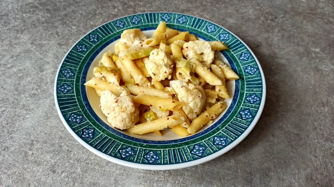 Une assiette de penne rigate au chou-fleur rôti et poireau
