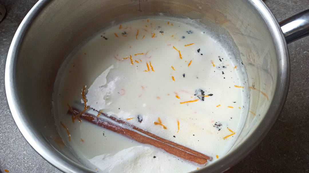 nfuser le lait avec la gousse et les graines de vanille, le zeste d'orange et le bâton de cannelle