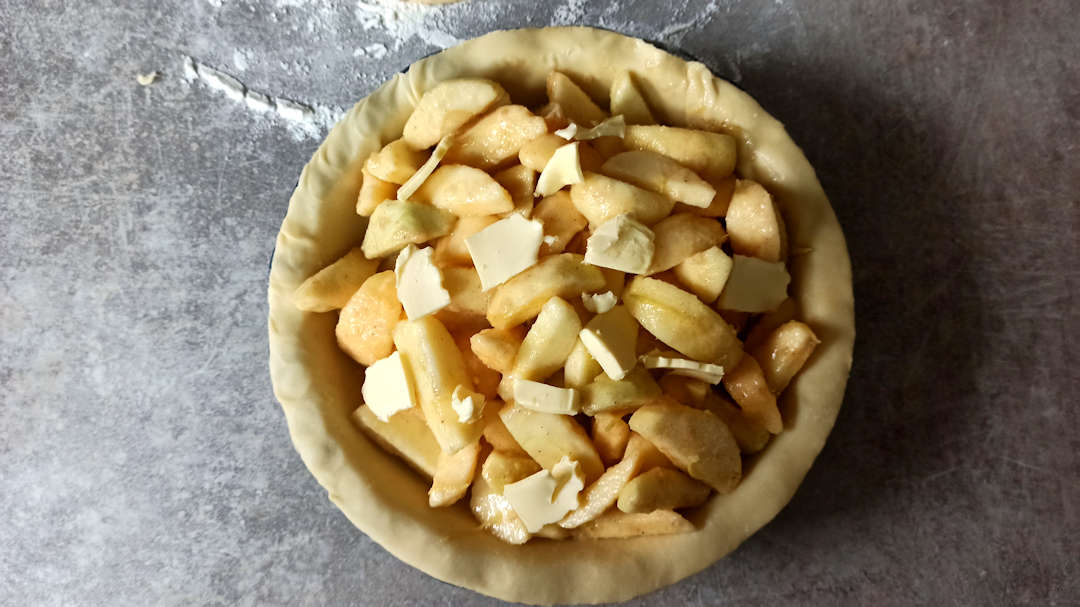 Parsemer de petits morceaux de beurre sur l'apple pie traditionnelle